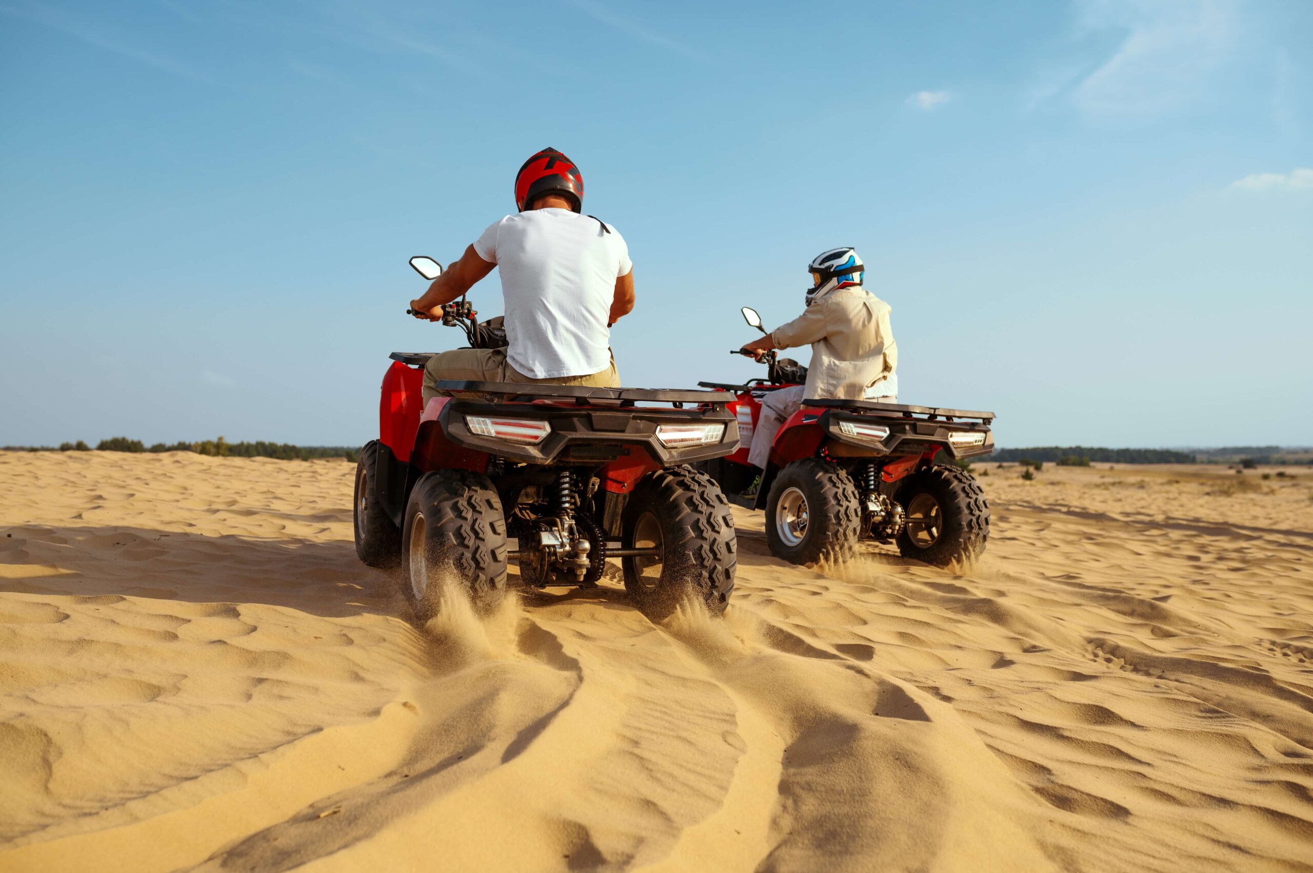 two-men-helmets-riding-atv-desert-sands (1)